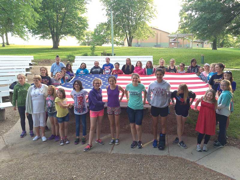 girls at camp with big American flag 